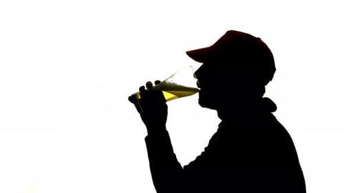 Bärtiger Mann in einer Kappe trinkt Bier aus einem Glas, Seitenansicht, Silhouette weißer Hintergrund