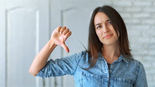 Woman Gives Thumbs Down Gesture Indoors