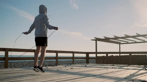 Young Adult Skipping Rope on Beach Boardwalk