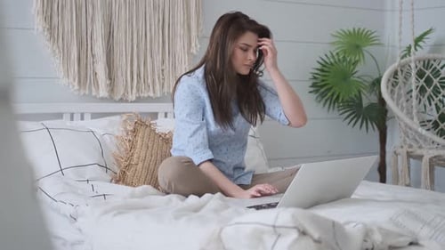 Woman Using Laptop on Bed in Bright Home