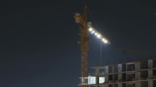 Building Construction at Night. Timelapse. Tower Crane on a Construction Site with Lighting