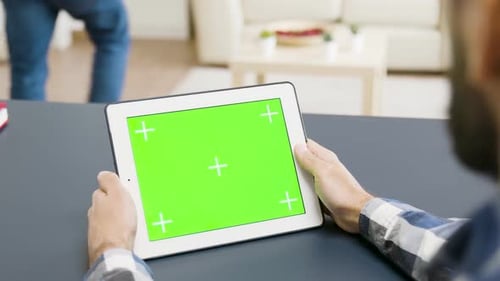 Over the Shoulder Shot of Man Holding a Tablet with Green Screen