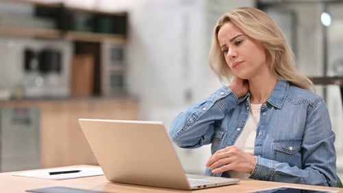Woman With Neck Pain Massaging Neck at Computer
