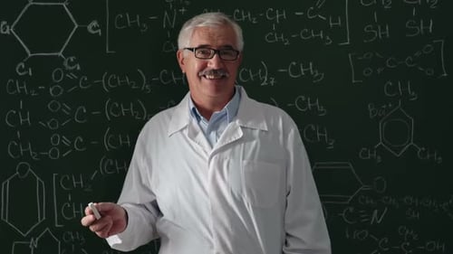 Professor Writes Chemistry Equations on Chalkboard, Smiling