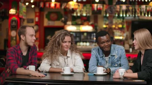 A Multinational Company of Friends Drinks Coffee and Talking in a Restaurant.