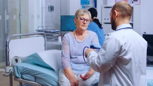 Doctor Checks Senior Woman's Blood Pressure in Hospital