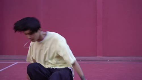 Young Adult Breakdancing Against a Red Wall