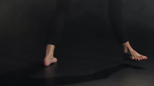 Bare Feet of Young Artist During Dance in Darkness