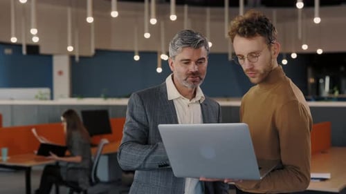 Men Discussing Laptop in Modern Open Office Space