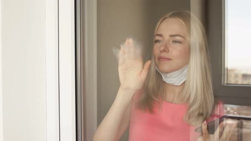 Woman with Mask Draws Heart on Window