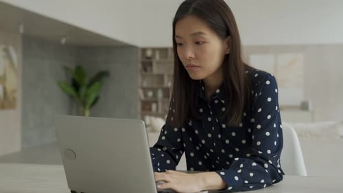 Excited Young Woman Typing on Laptop at Home