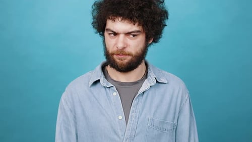 Confused Young Adult Male Gesturing Questioning on Blue