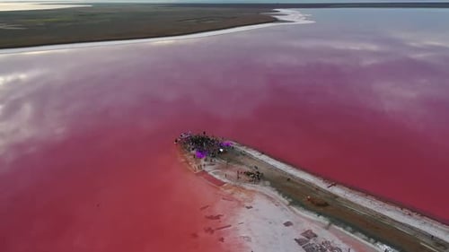 Lindo lago rosa, reflexos, céu, pessoas festejando na costa