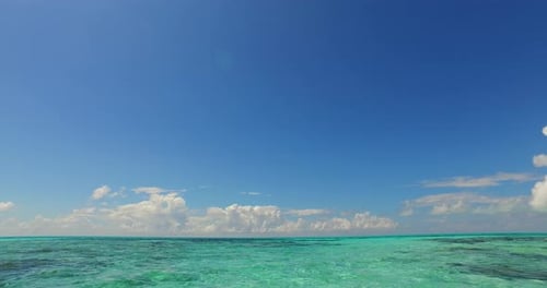Daytime fly over copy space shot of a white paradise beach and blue water background in vibrant 4K