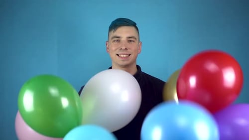Happy Young Adult Smiling Behind Colorful Balloons