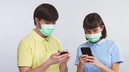 Man and Woman Using Phones Wearing Face Masks