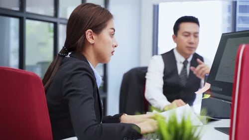Asian happy young business woman and man typing on keyboard working together as team in office.