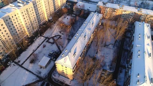Different Buildings with Snow Roofs and Yard with Bare Trees