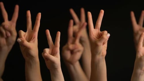 Hands Raise Victory Sign on Black Background