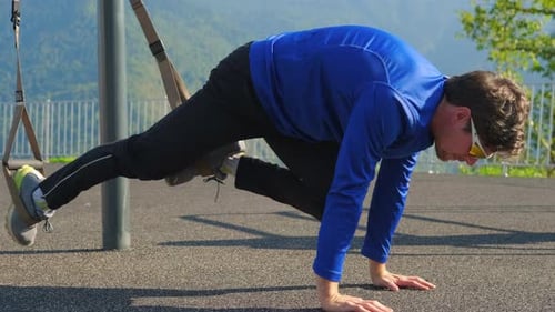 Professional Sportsman is Training with TRX Straps on Open Sport Area