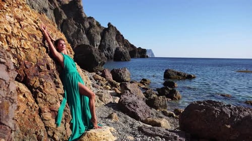 Side View a Young Beautiful Sensual Woman with Black Hair in a Long Mint Dress Posing on a Beach