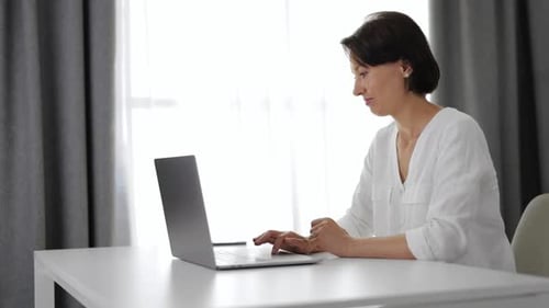 Woman Typing at Laptop in Bright Home Office