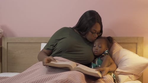 Woman Reads to Child in Bed