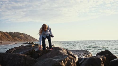 Photographer Clambering Over Rocks By Sea