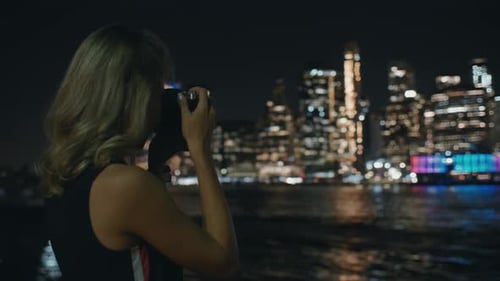 Woman Takes Pictures of City Skyline at Night