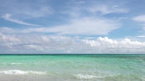 ein Horizont aus klaren blauen türkisfarbenen Meereswellen mit weißen flauschigen Wolken am strahlend blauen Himmel in der