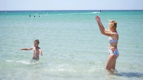 Happy Family Has Fun Playing in the Sea Creating Splashes