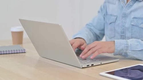 Man Opens Laptop and Types at Desk
