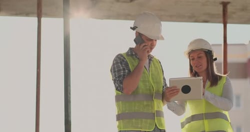 The Controller is a Man of a Building Under Construction Talking on the Phone with Management and