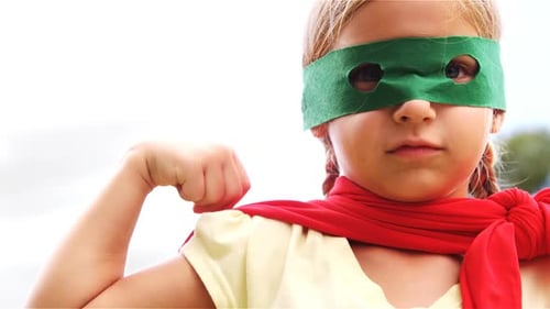 Confident Little Girl Wearing Superhero Costume Flexing Muscle