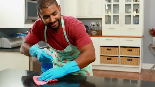 Man Cleaning Kitchen Counter in Floral Apron