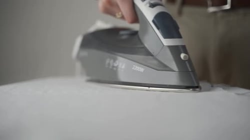 A Seamstress Woman Makes a Wet Heat Treatment of the Fabric with an Iron