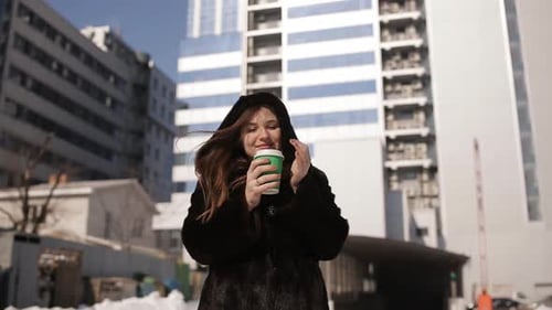 Young Woman Drinks Beverage in Urban Winter Setting