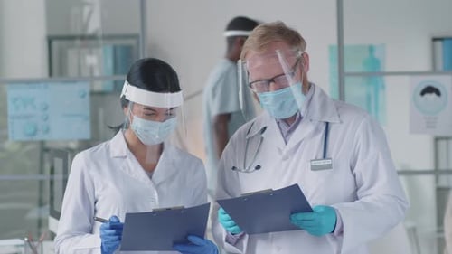 Male and Female Doctors in Protective Uniform Talking in Clinic