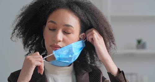 Woman Takes Off Blue Face Mask Indoors