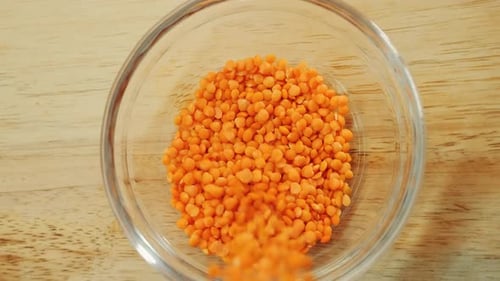 Orange Lentils Being Poured into Glass Bowl
