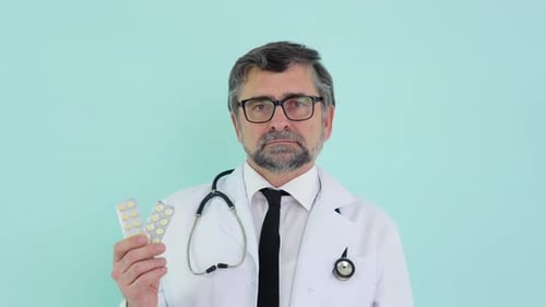 Doctor Holds Pills Against Light Blue Background