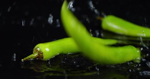 Green Chili Peppers Falling in Water with Splashes.