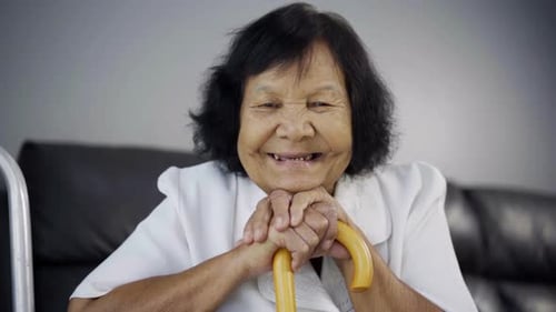 Senior Woman Smiling Holding a Walking Cane Indoors