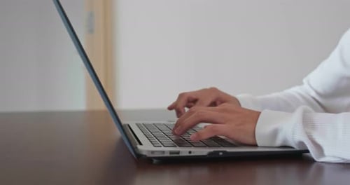 Hands Typing on Laptop Computer Keyboard at Desk