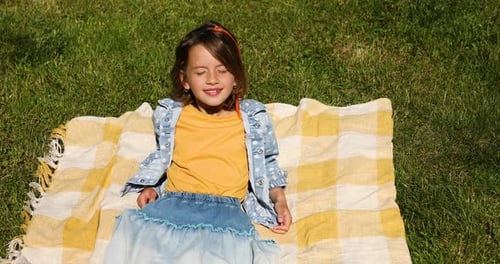 Child lying on the blanket, on the grass in the sun day, take sunbathes on backyard