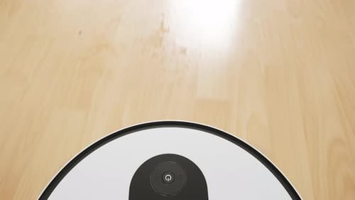 Top View of a White Robotic Vacuum Cleaner Cleaning Up the Wooden Floor