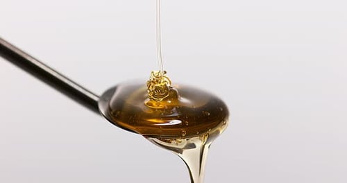 900378 Honey Flowing on Spoon against White Background, Slow Motion 4K