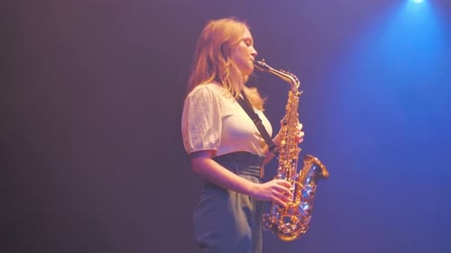 Woman Plays Saxophone on Stage in Studio