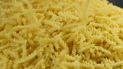Spiralnudeln, die über einen Haufen trockener Makkaroni verschüttet werden