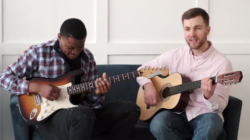 Young Adults Playing Guitars Together on Blue Couch